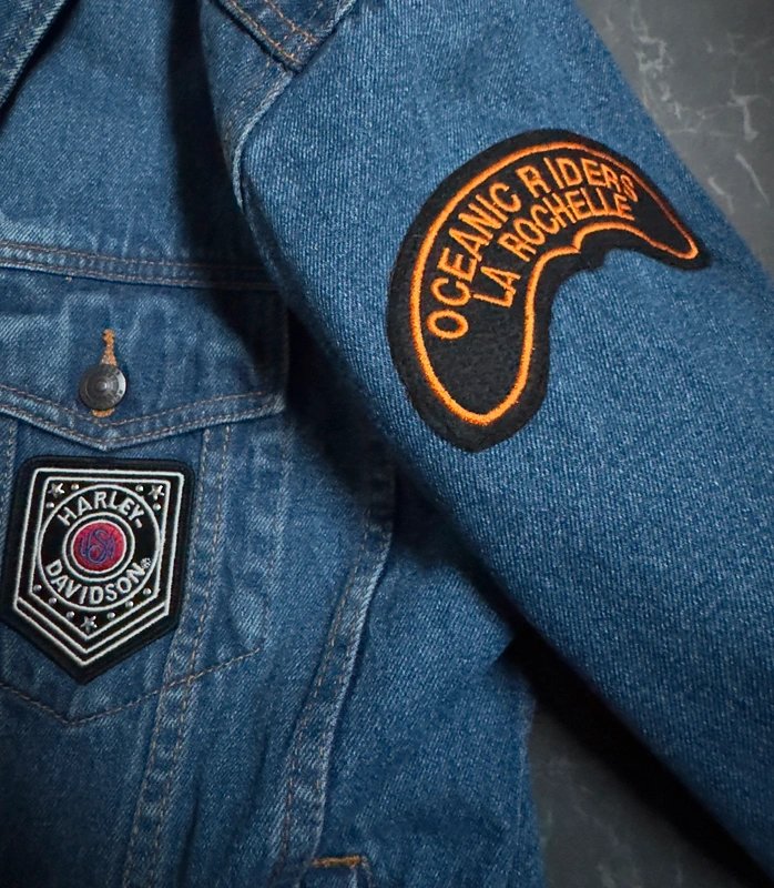 Close-up of custom embroidered Oceanic Riders and Harley Davidson patches on a classic denim jacket